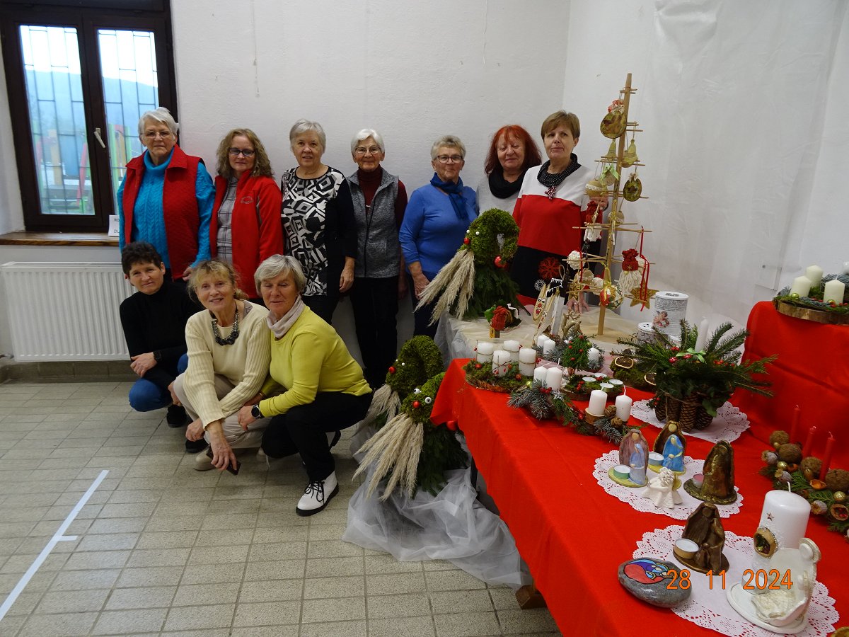 Skupina žensk, poleg pa adventni venčki in druga praznična okrasitev.