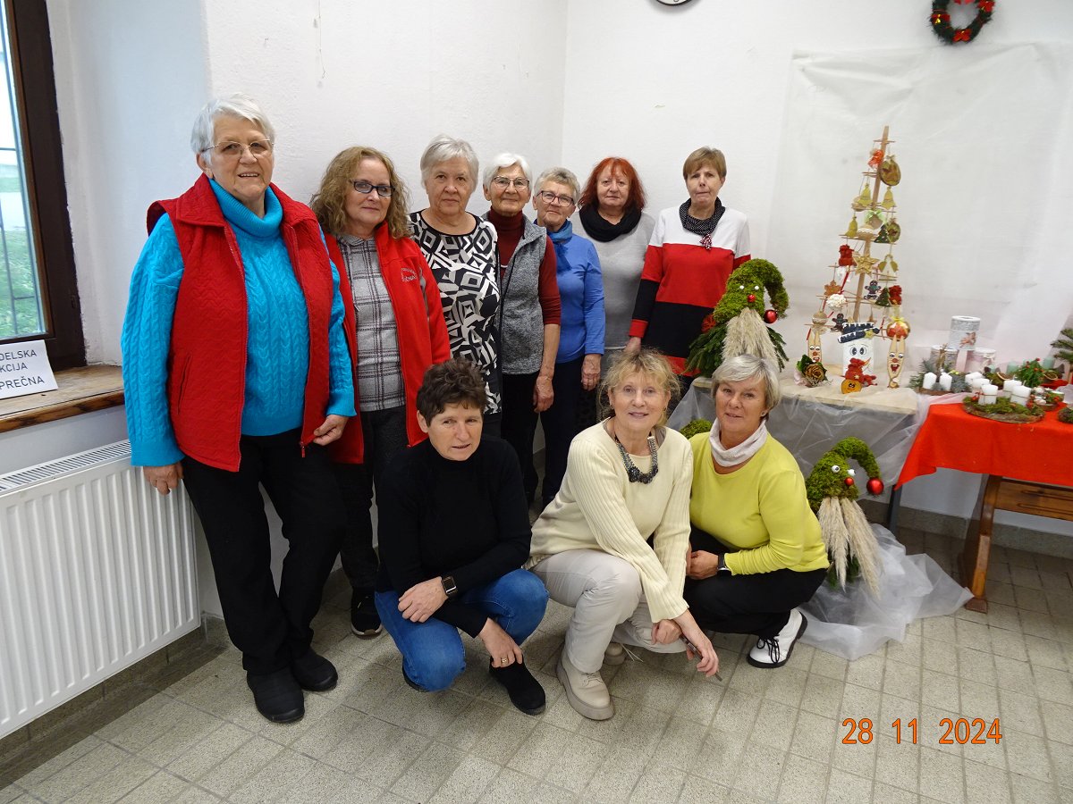 Skupina žensk, poleg pa adventni venčki in druga praznična okrasitev.